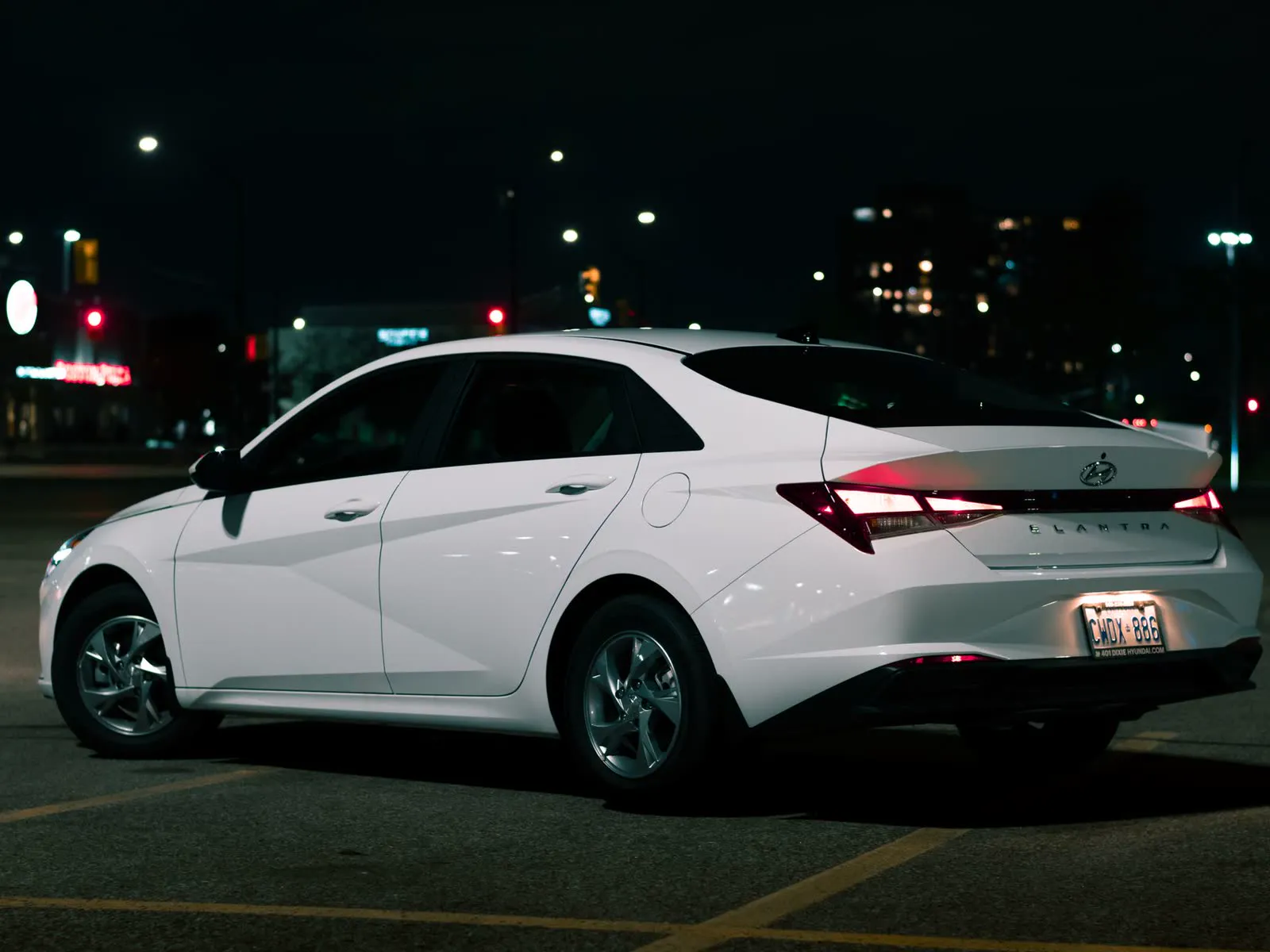White Hyundai Elantra sedan, rear three-quarter view at night