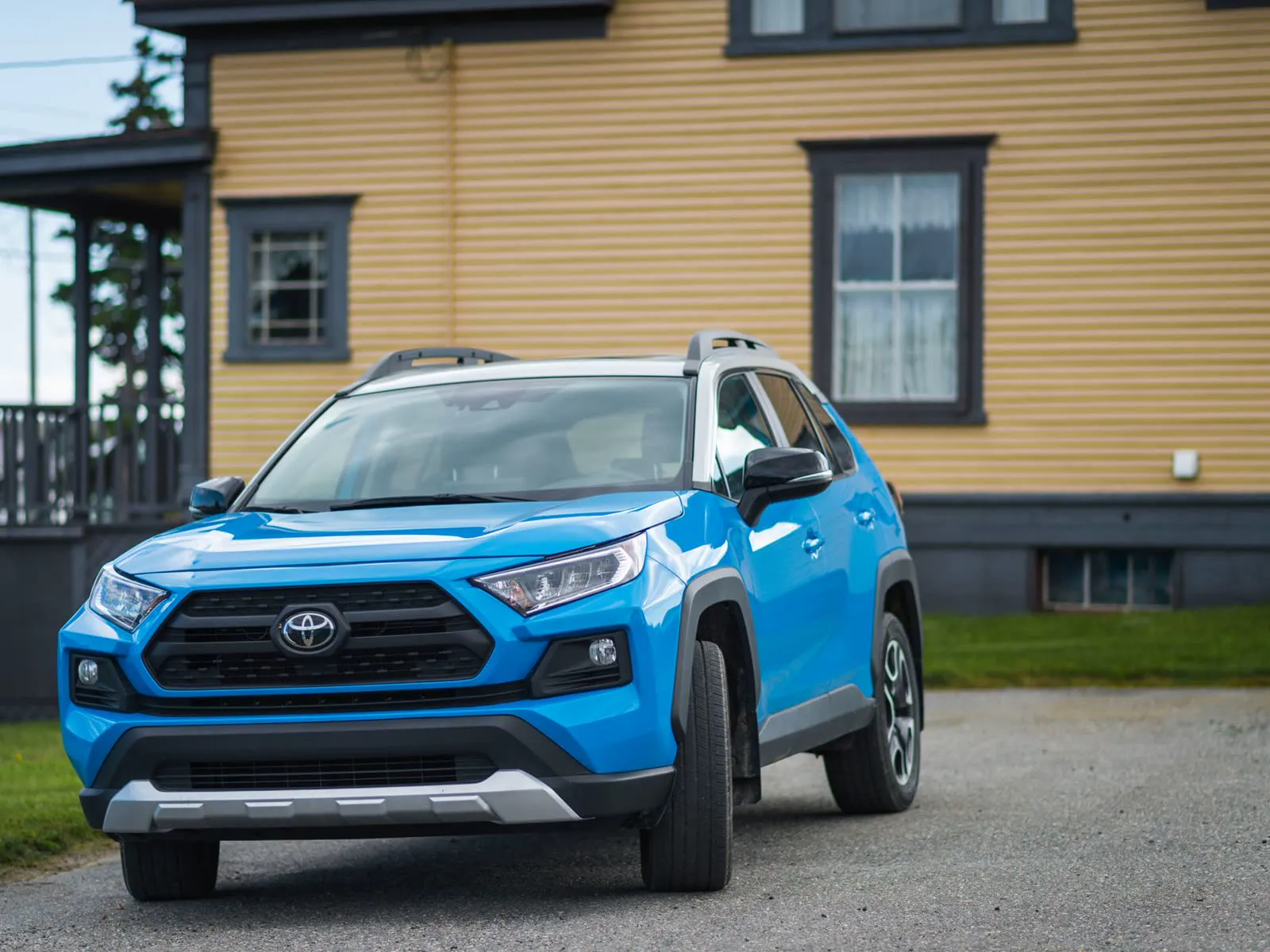 2021 Toyota RAV4 SUV in blue, front three-quarter view parked near a house